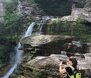 The author wearing a backpack taking a photo of a waterfall